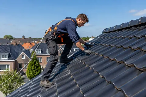Dakdekker controleert de dakpannen van een rijtjeshuis